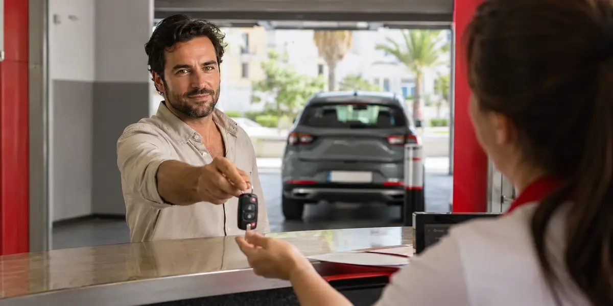 conductor devolviendo las llaves de un coche de alquiler en el mostrador de una oficina de rent a car