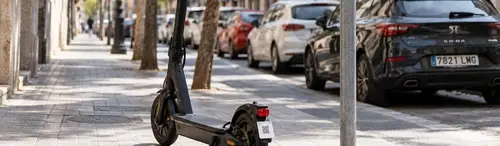 Etiqueta identificativa en la rueda trasera de un patinete eléctrico aparcado en una calle de España, necesaria para el seguro obligatorio del patinete
